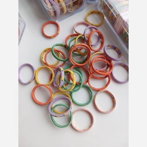 Clear storage containers filled with colorful rainbow thin elastic hair ties in various solid and multicolor combinations for girls