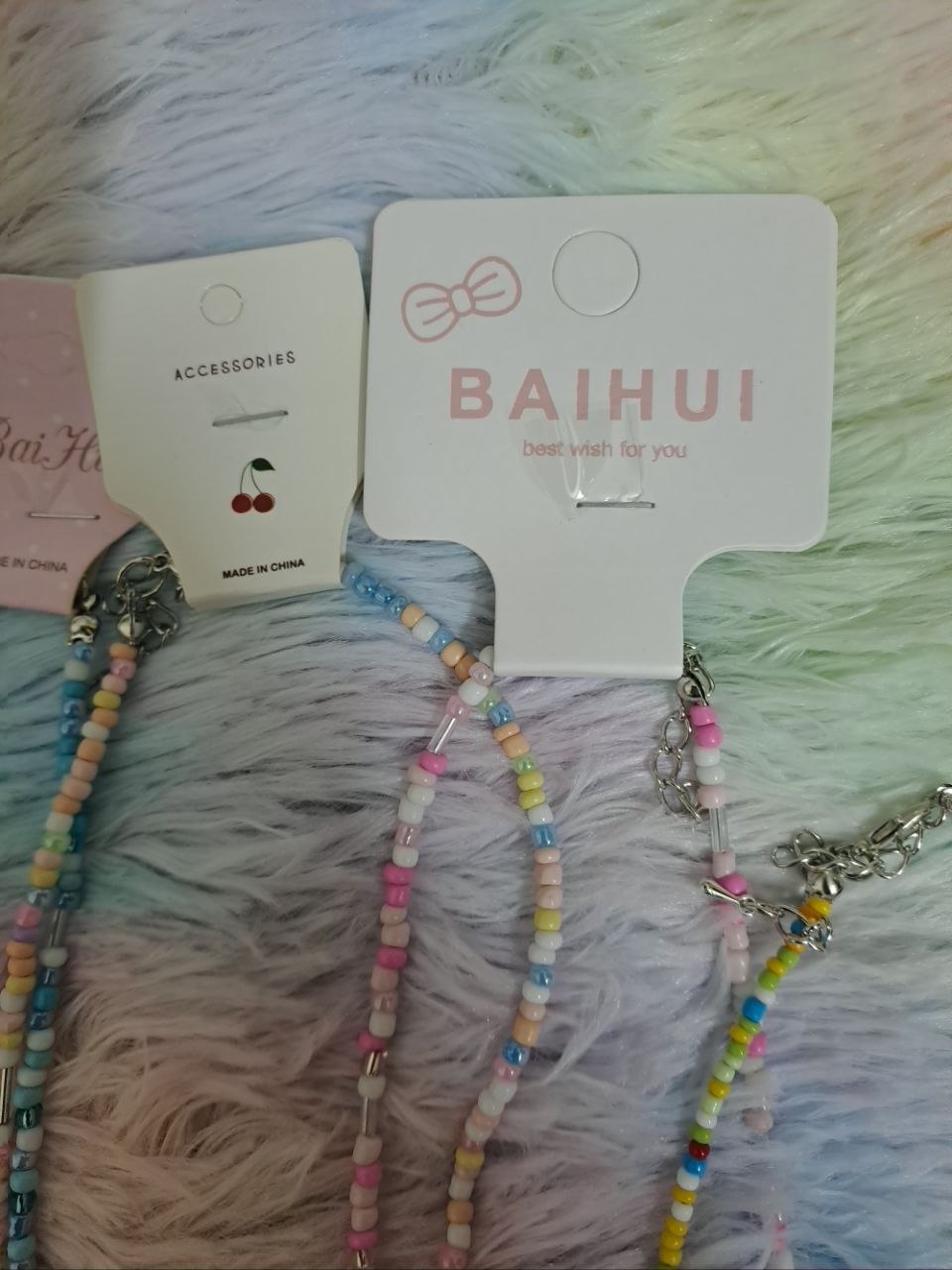 Colorful beaded necklaces with tiny rainbow beads and adorable charm pendants including smiling faces, flowers, hearts, and rainbows for girls