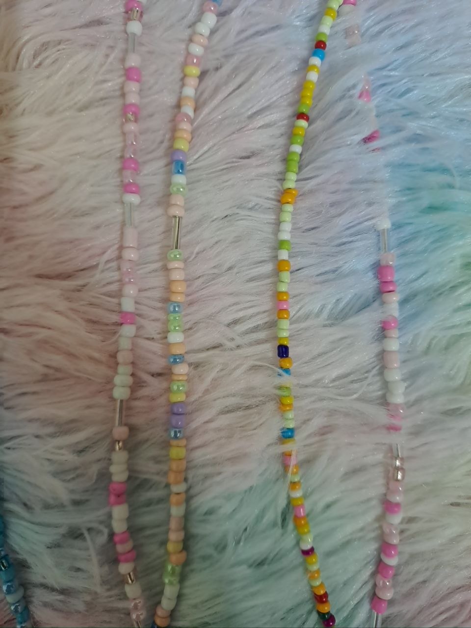 Colorful beaded necklaces with tiny rainbow beads and adorable charm pendants including smiling faces, flowers, hearts, and rainbows for girls