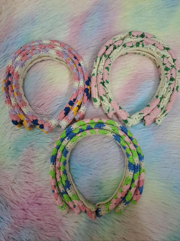 Handcrafted crocheted headbands with intricate braided floral patterns in multicolor combinations including pink, green, blue, cream, and purple for girls