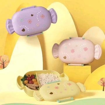 Goodday candy-shaped floral kids bento lunch box in lavender purple, blush pink, and butter yellow variants, showing divided compartment interior with food, delicate botanical floral lid illustration, and included chopsticks, BPA-free children's tiffin box