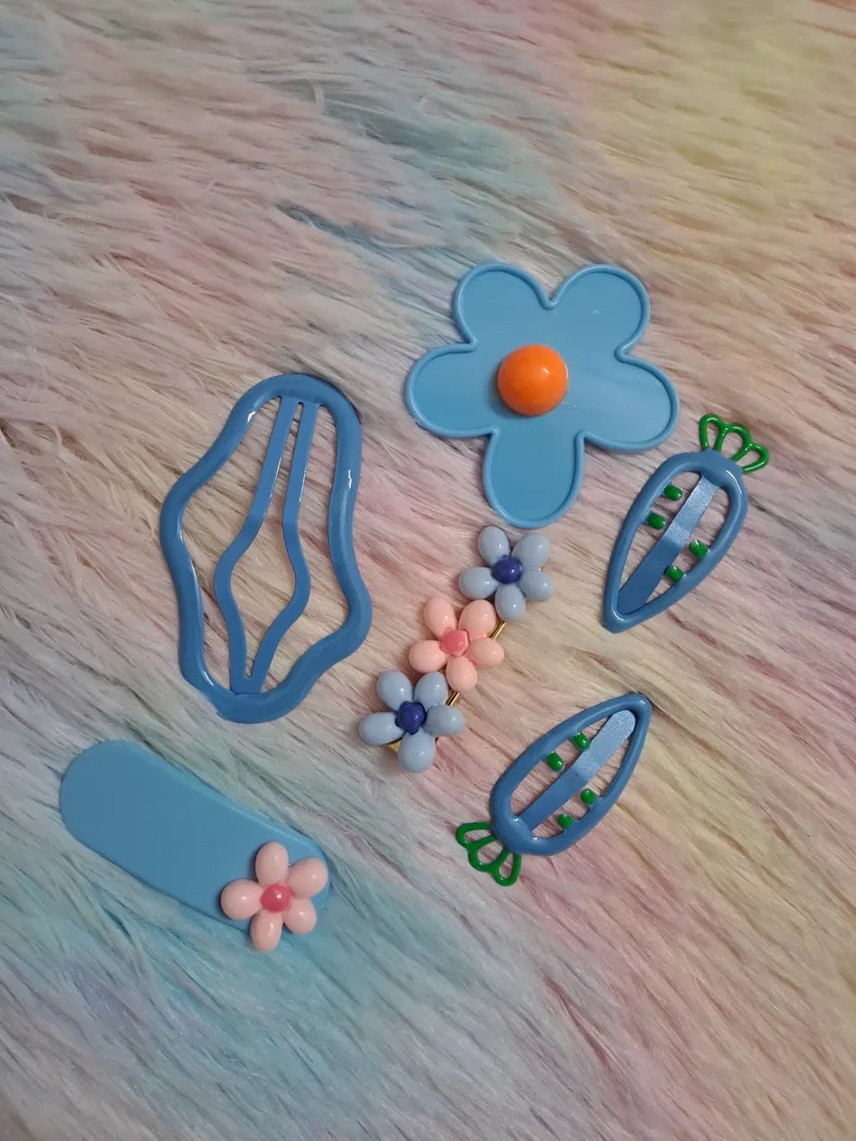 kawaii hair clip set 6 pieces including large retro daisy with orange centre, abstract wavy oval clip, small flower snap clip, two carrot-shaped clips with green tops, and beaded floral cluster pin in coordinated sky-blue palette