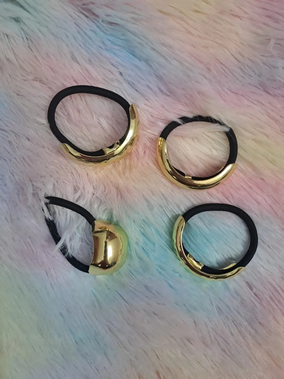 Gold metal charm black elastic hair tie set of 4 pieces featuring oversized sculpted irregular gold charm pieces in high-polish reflective finish on thick black elastic, luxury ponytail holder hair accessories