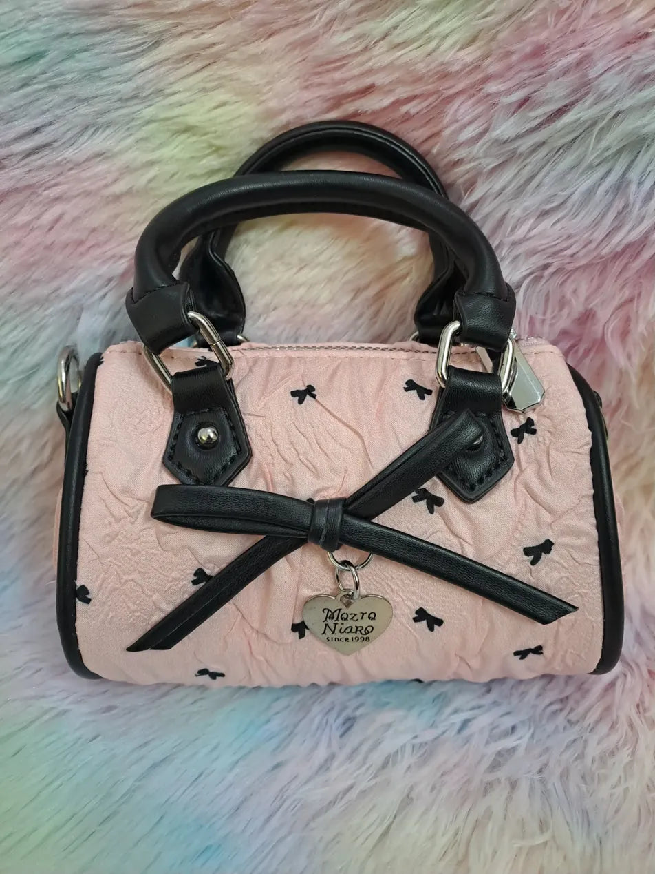 Mazra Niaro pink quilted mini handbag with black bow pattern, black trim, decorative bow and adjustable shoulder strap for girls
