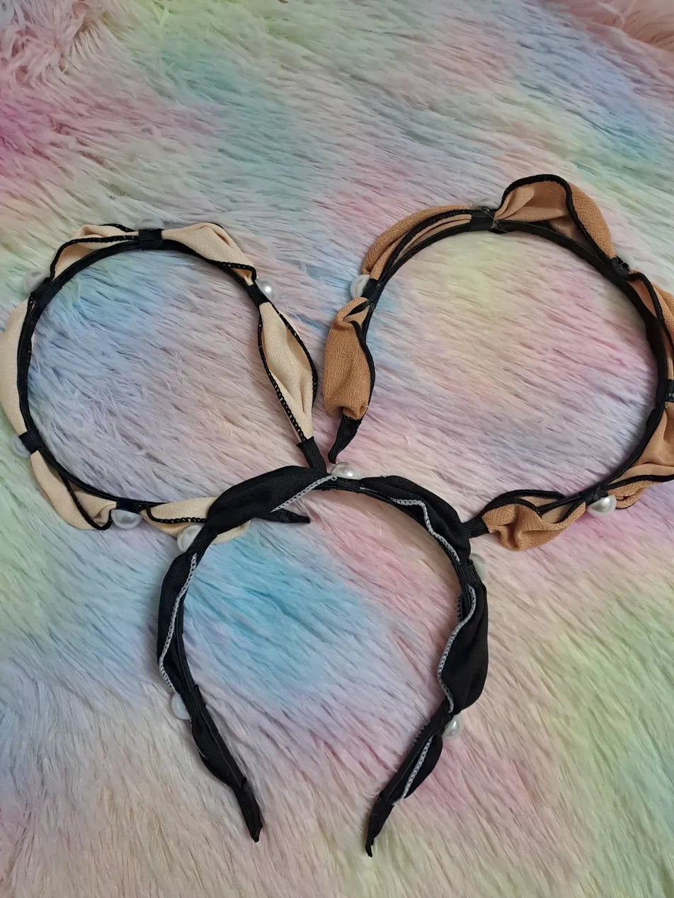 Satin ruched cat ear pearl headband set in three colourways: cream and black, tan and black, and all-black, with gathered satin fabric forming decorative ear bows and pearl accents along firm inner band, elegant hair accessory